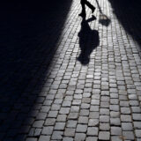 Eine Person läuft in der Dunkelheit über einen Gehweg.