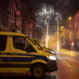 Hinter einen Streifenwagen der Polizei leuchten Feuerwerkskörper am Himmel