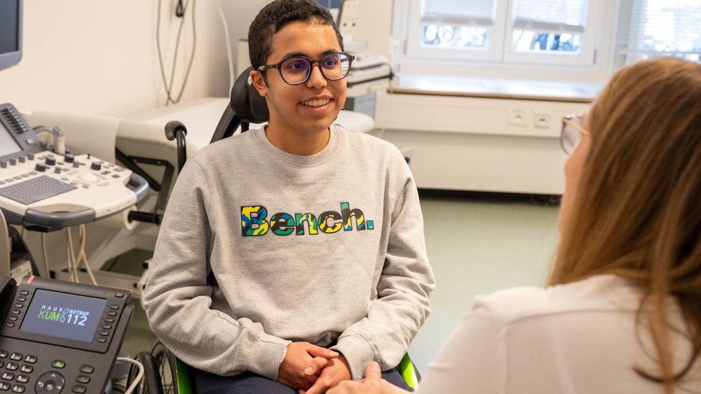 Der 17-jährige Abhay hat  seit seiner Geburt eine schwere Muskelerkrankung und sitzt im Rollstuhl. Oberärztin Astrid Blaschek (rechts) betreut ihn seit vielen Jahren.