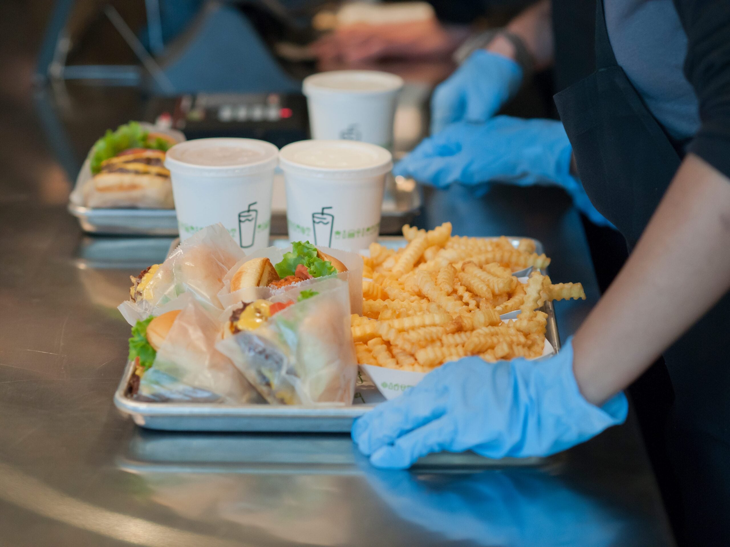 Image shows a Shake Shack tray with two drinks, two burgers, and two baskets of crinkle cut fries.