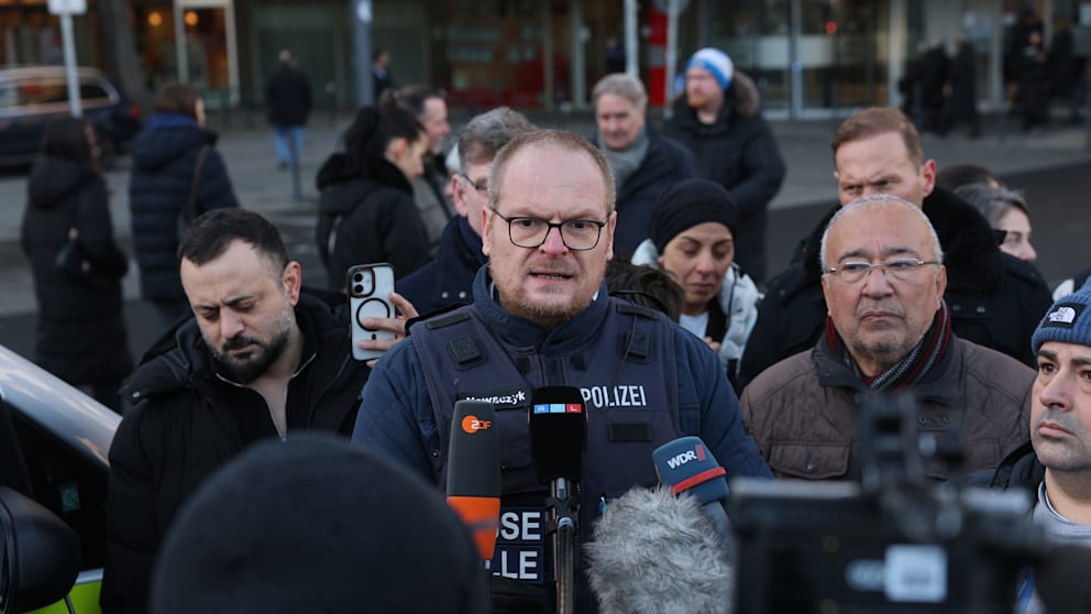 Polizeisprecher Thomas Nowaczyk spricht vor der Sparkassenfiliale zu Journalisten
