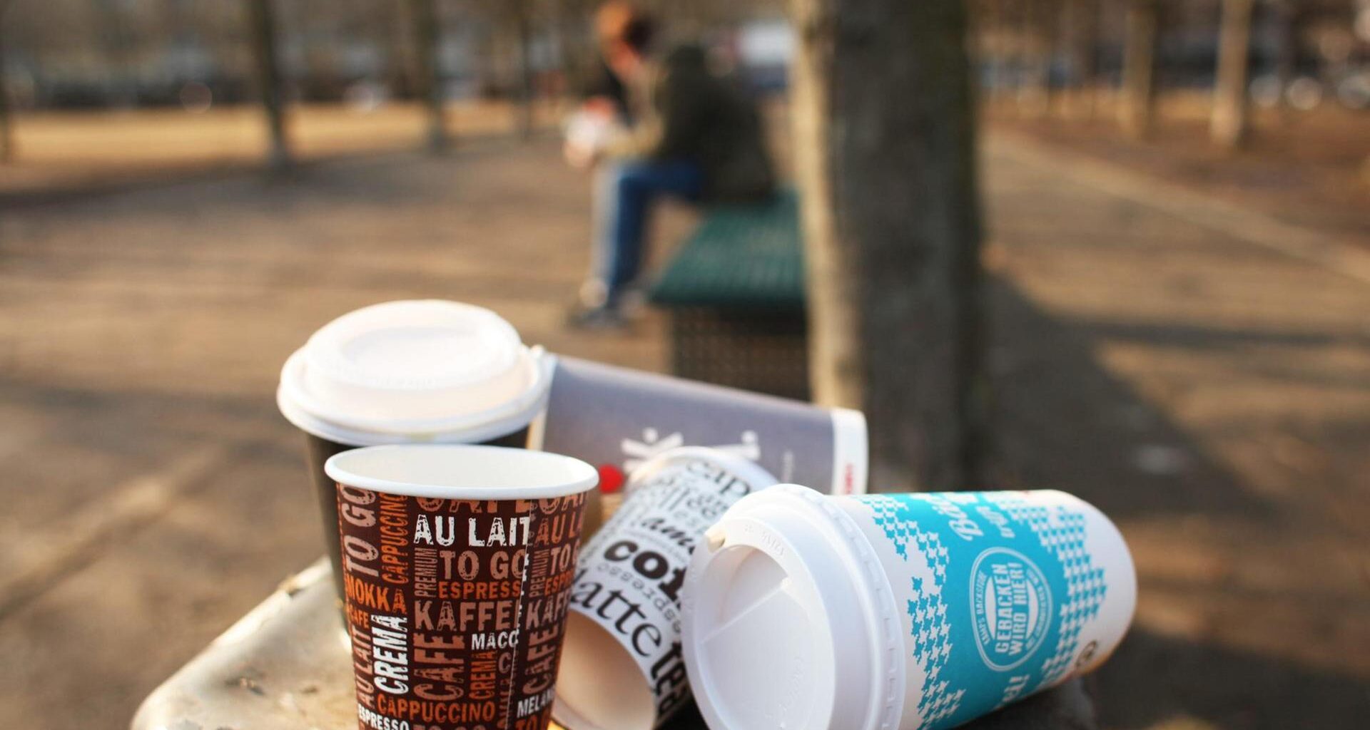 Mehrere Einwegbecher auf einem überfüllten Mülleimer.