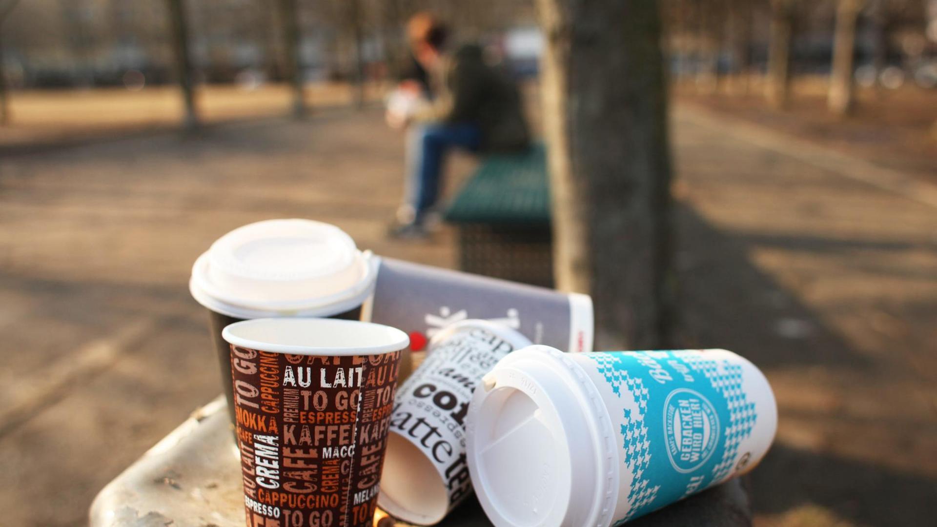 Mehrere Einwegbecher auf einem überfüllten Mülleimer.