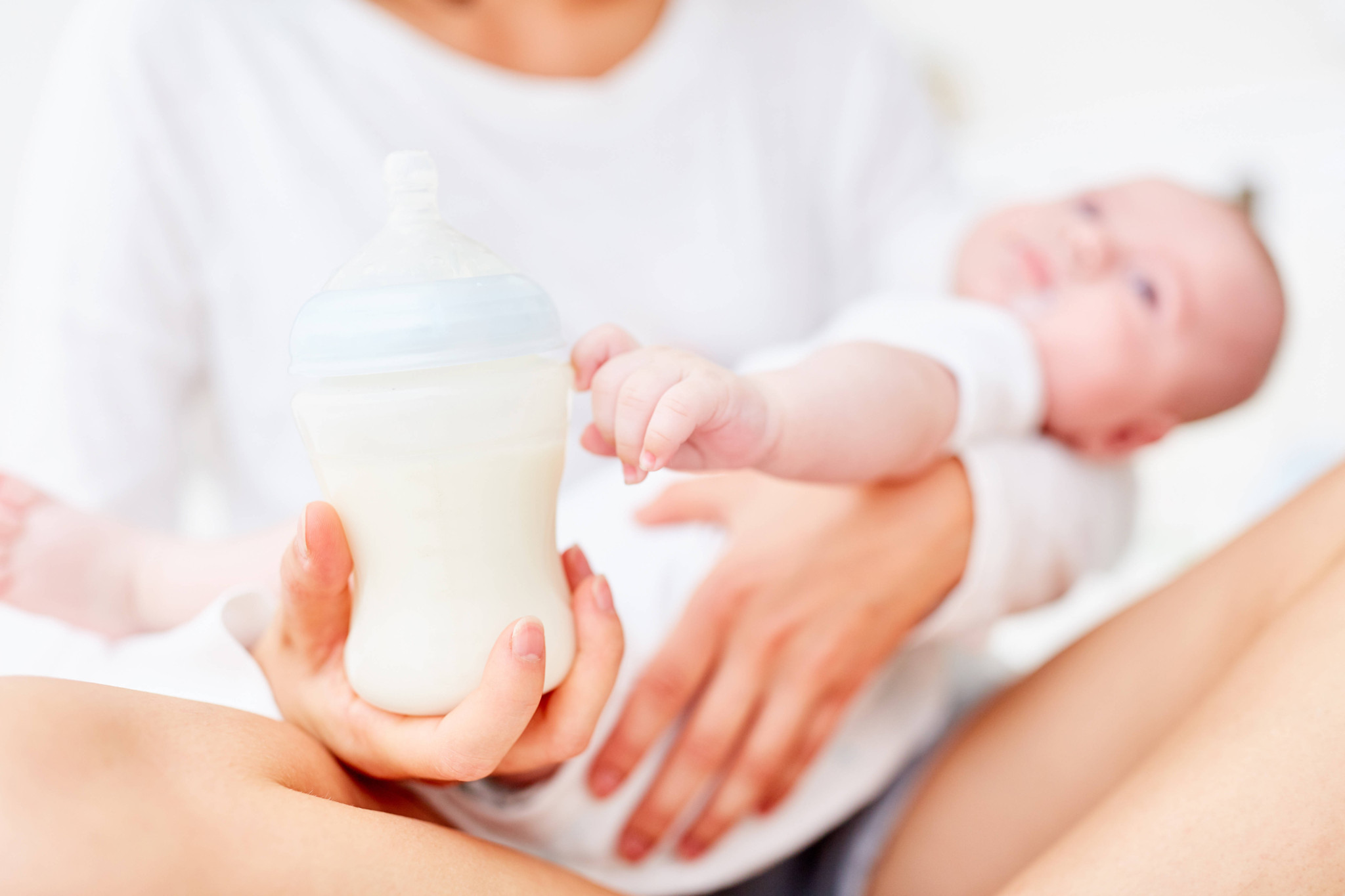 Mutter füttert ihr Baby mit einem Fläschchen Babymilch.