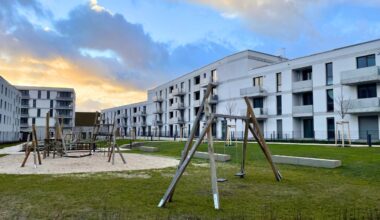 Wohnsiedlung Buckower Felder: Weiß verputzte Häuser mit Grünfläche und Spielplätzen.