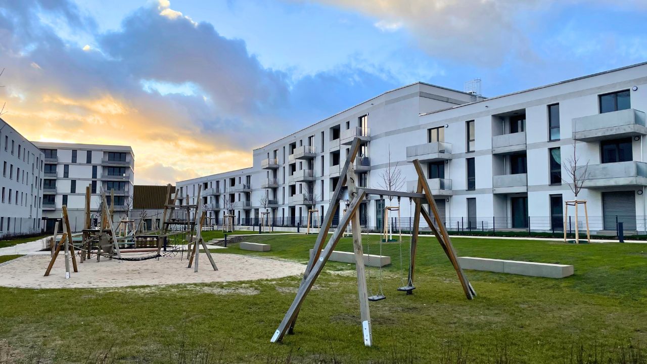 Wohnsiedlung Buckower Felder: Weiß verputzte Häuser mit Grünfläche und Spielplätzen.