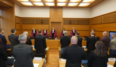 Gerichtssaal, Kläger und Beklagte, Richter in roten Roben.