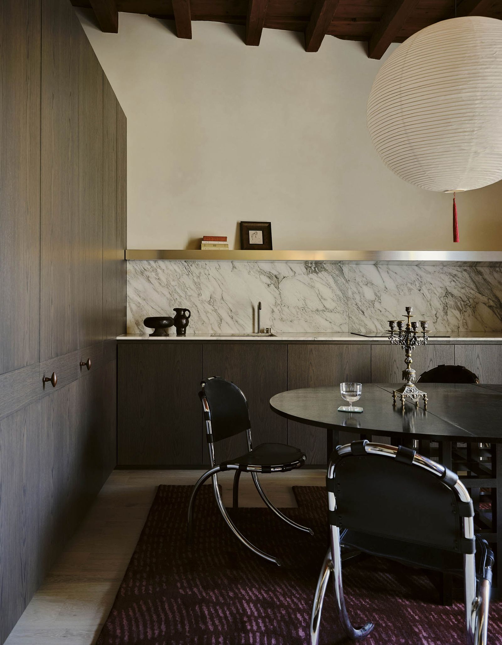 Die Küche ist in einem dunklen Ton gehalten und auf dem Boden liegt ein dunkelroter Teppich