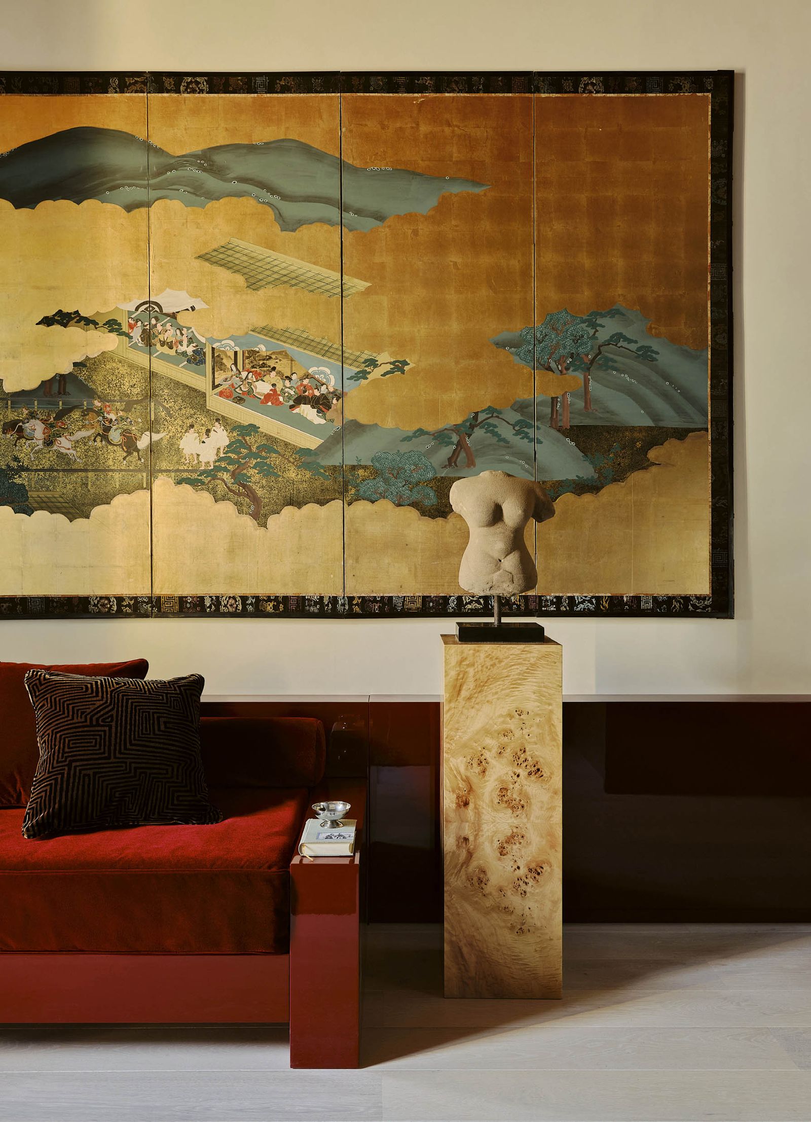 Im Wohnzimmer steht ein rotes Sofa und daneben eine Skulptur