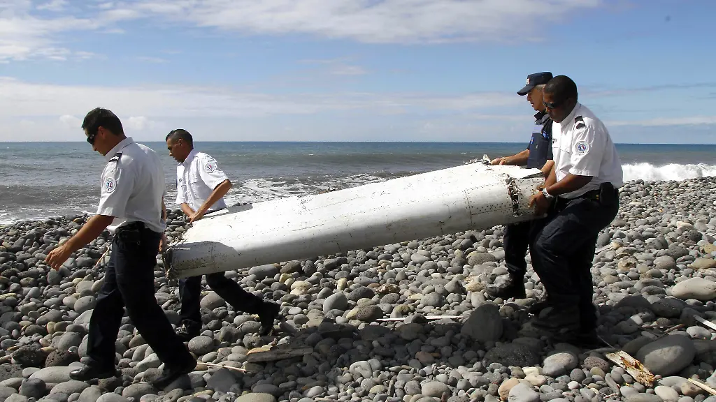 Techniker-tragen-ein-Wrackteil-die-Fluegelklappe-eines-Flugzeugs-ueber-einen-Strand-bei-Saint-Andre-de-la-Reunion-Die-Suche-nach-dem-Wrack-des-seit-Maerz-2014-verschollenen-Fluges-MH370-der-Malaysia-Airlines-soll-am-Dienstag-fortgesetzt-werden-Die-Spezialfirma-Ocean-Infinity-will-55-Tage-lang-suchen