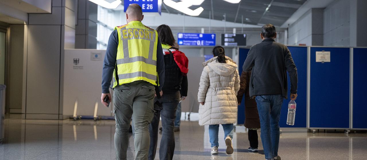 Eine Familie wird von Beamten der Bundespolizei (l) zu einem Abschiebeflug nach Pakistan begleitet.