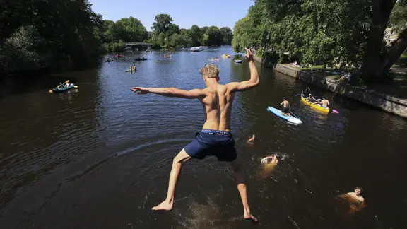 Ein junger Mann springt in die Alster.