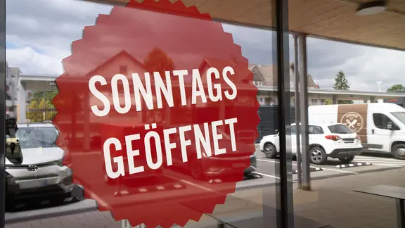 "Sonntags geöffnet" steht an der Schaufensterscheibe eines Geschäftes.