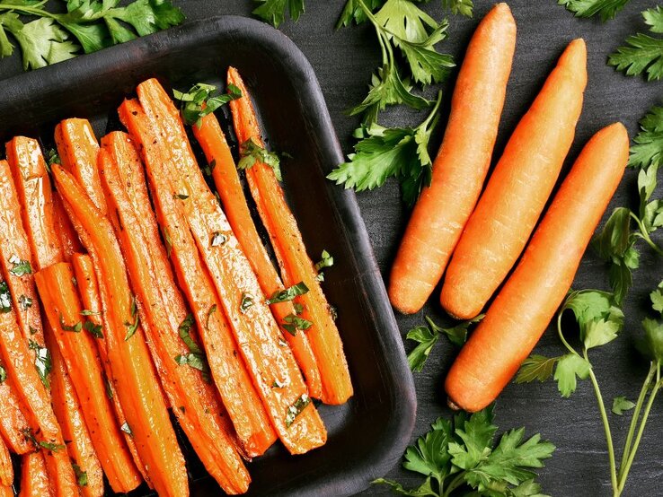 Blech mit Ofen-Karotten und rohe Karotten. | © Getty Images Pro/ Tatiana Volgutova via Canva.com