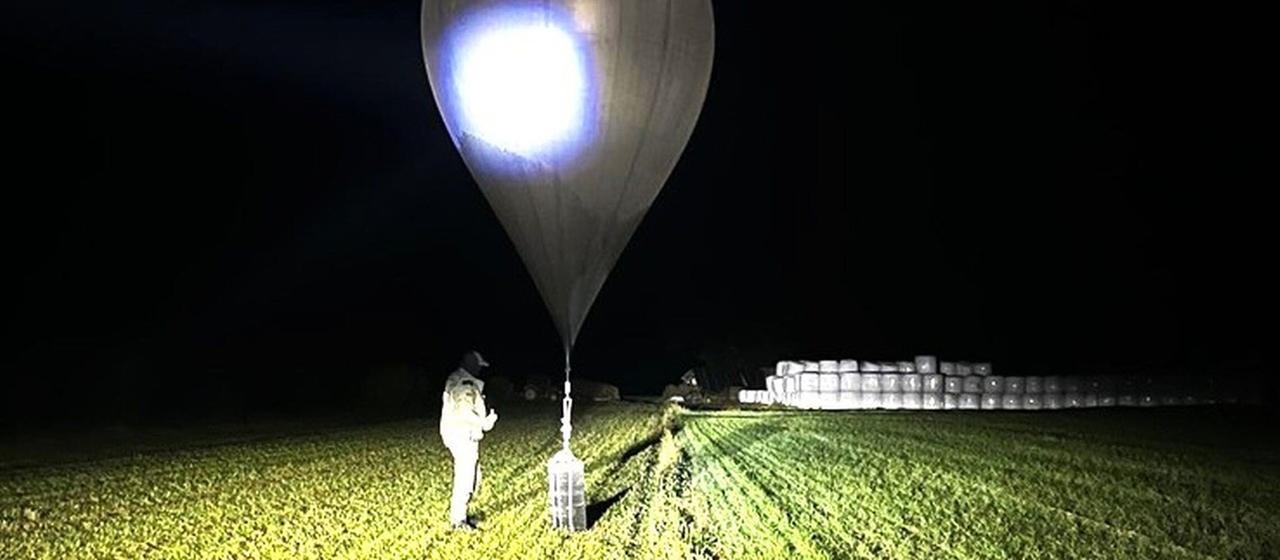 Ein litauischer Beamter inspiziert auf einem Feld einen Ballon. | AP Ein litauischer Beamter inspiziert auf einem Feld einen Ballon.