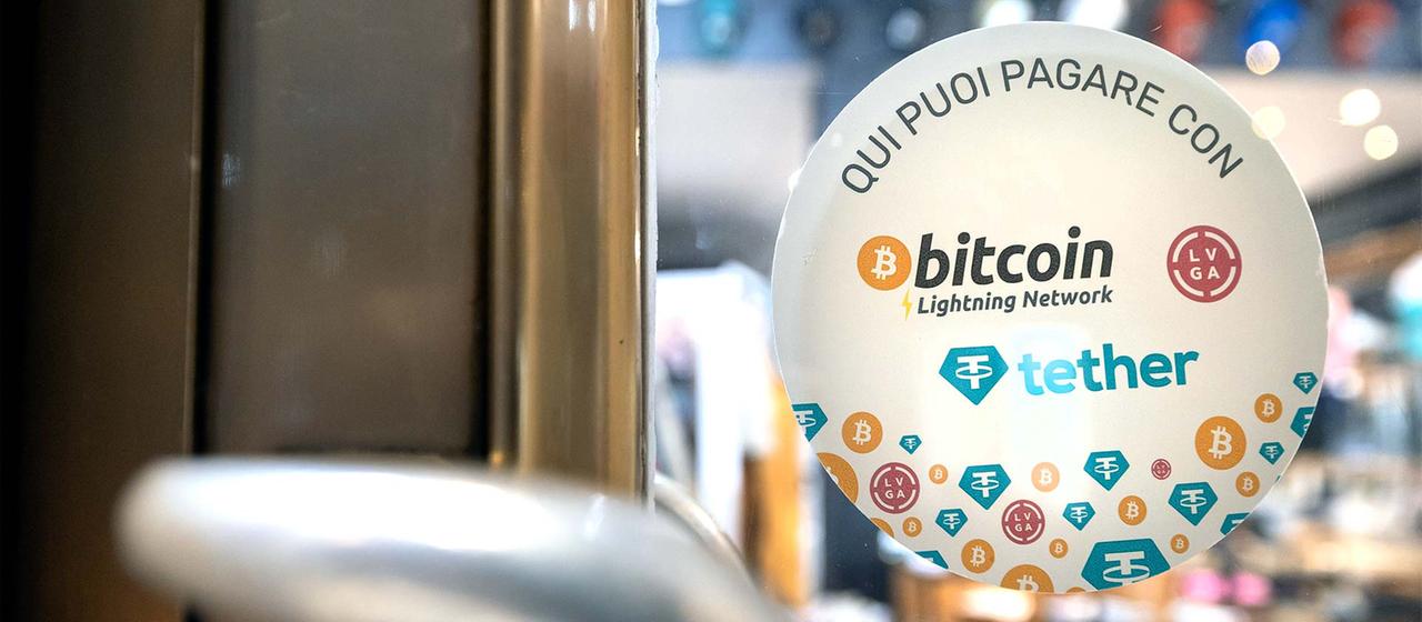 Aufkleber mit der Aufschrift „Hier können Sie mit Bitcoin bezahlen“, in Lugano. | picture alliance/KEYSTONE Aufkleber mit der Aufschrift „Hier können Sie mit Bitcoin bezahlen“, in Lugano.