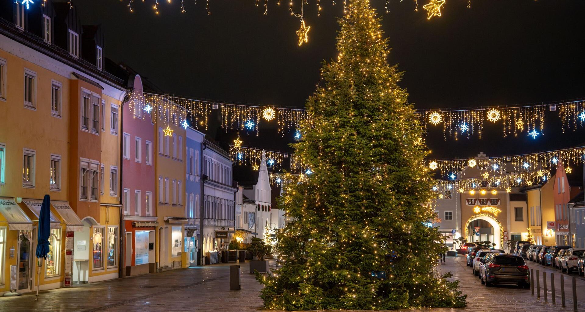 Es ist dunkel. Der Baum mit hunderten goldenen Lichtern steht in der Mitte des Platzes, der von Altstadt-Häusern eingerahmt ist.