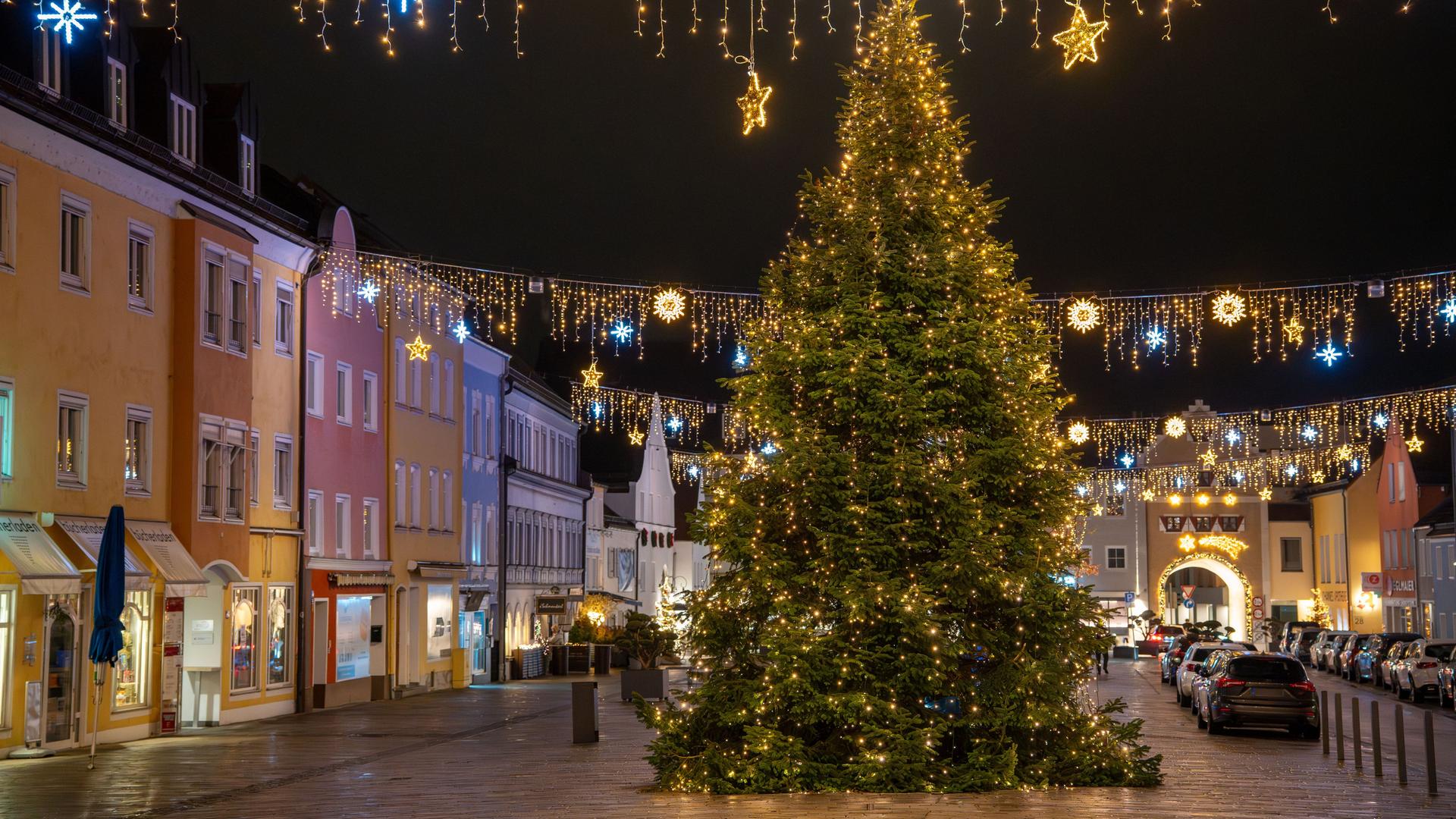 Es ist dunkel. Der Baum mit hunderten goldenen Lichtern steht in der Mitte des Platzes, der von Altstadt-Häusern eingerahmt ist. Es ist dunkel. Der Baum mit hunderten goldenen Lichtern steht in der Mitte des Platzes, der von Altstadt-Häusern eingerahmt ist.