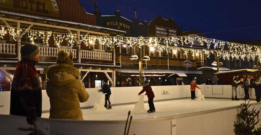 Schlittschuhlaufen zwischen Saloon-Fassaden und Lichterketten bietet eine einzigartige winterliche Kulisse.