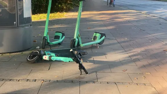 E-Scooter liegen und stehen auf dem Gehweg.