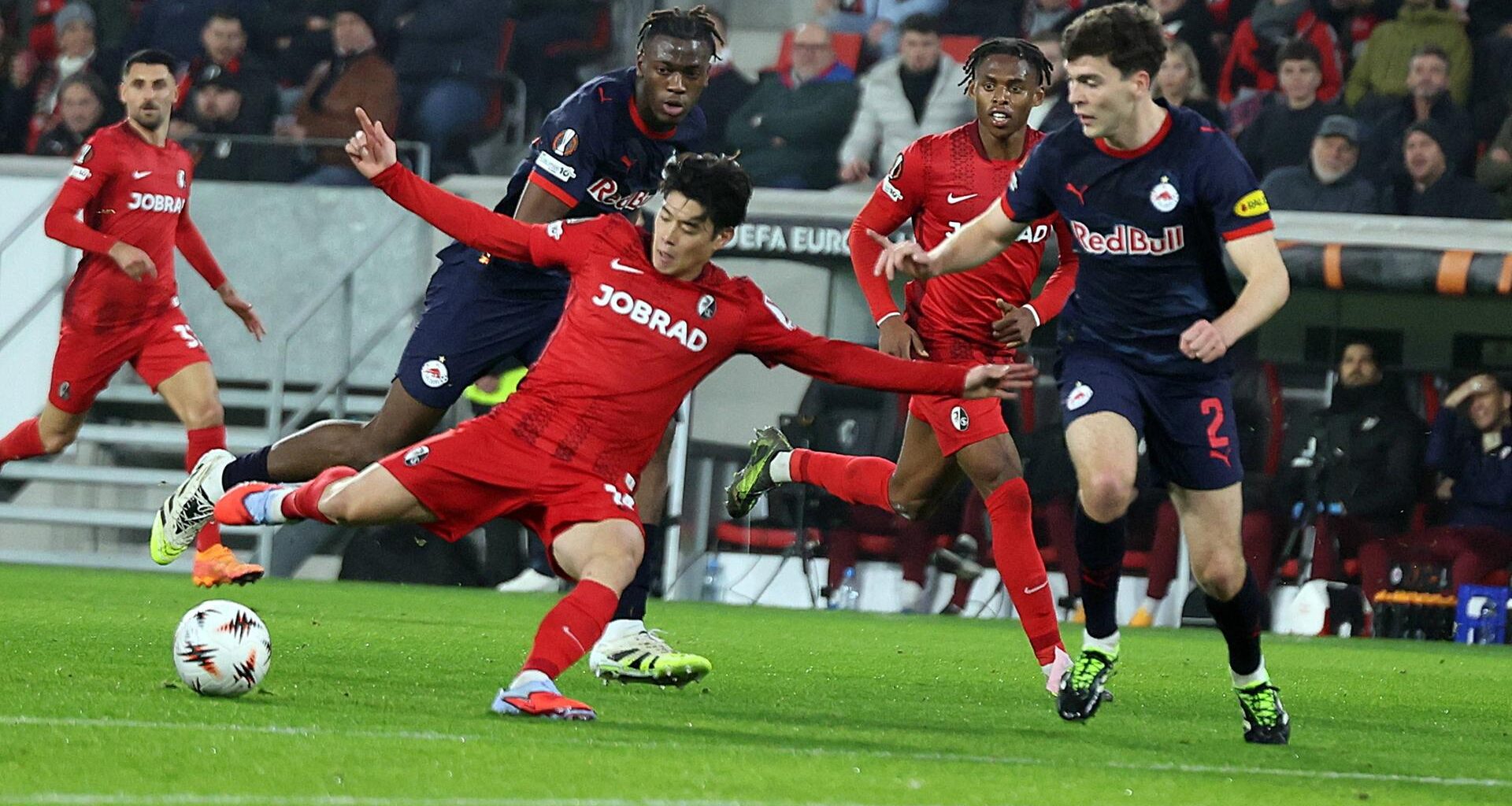 Yuito Suzuki vom SC Freiburg schießt im Fallen den Ball.