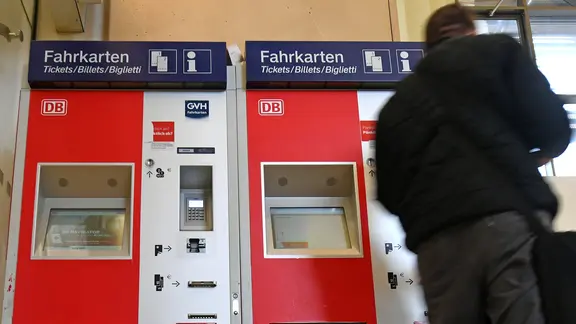 Ein Mann kauft einen Fahrausweis an einem Fahrkartenautomaten der Deutschen Bahn.