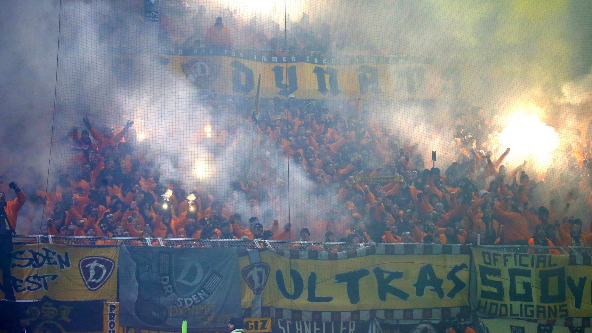 Fans von Dynamo Dresden brennen Pyrotchenik ab und werfen Feuerwerkskörper auf den Rasen.