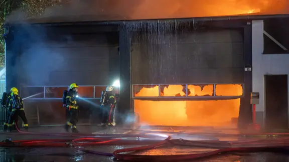 Einsatzkräfte der Feuerwehr löschen einen Brand in einer Lagerhalle in Barsbüttel.