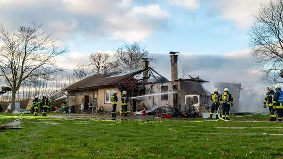 Feuerwehrleute löschen ein brennendes Wohnhaus