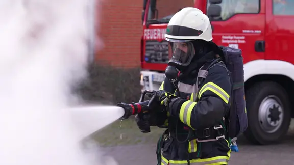 Das Bild zeigt eine Feuerwehrfrau im Einsatz.