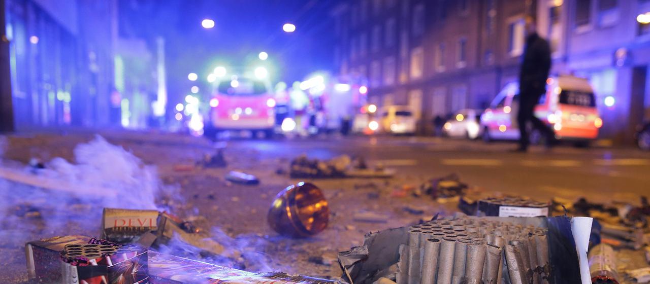Abgebrannte Böller liegen nach der Silvesternacht auf der Straße im Hintergrund sind Feurwehrfahrzeuge zu sehen. | dpa Abgebrannte Böller liegen nach der Silvesternacht auf der Straße im Hintergrund sind Feurwehrfahrzeuge zu sehen.