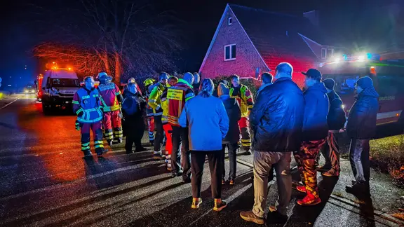 Anwohner und Einsatzkräfte der Feuerwehr stehen bei Dunkelheit bei einer Evakuierung nach Gasleck im Wohngebiet in Oldenburg.