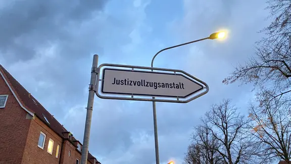 Ein weißes Schild auf dem steht: Justizvollzugsanstalt