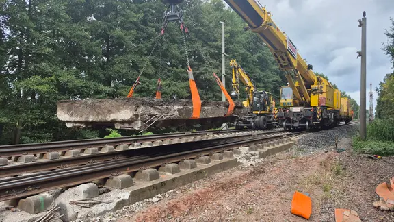Ein Eisenbahndrehkran hebt eine Betonplatte aus dem Gleisbett bei Wittenberge.