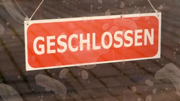 An einer Glastür hängt ein Geschlossen-Schild.