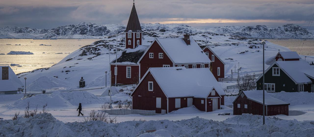 Eine Frau geht in der Nähe einer Kirche in Grönland. 