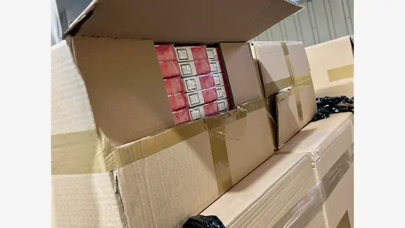 Ein geöffneter Karton voll mit Zigaretten-Päckchen steht auf weiteren Pappkartons beim Zoll.
