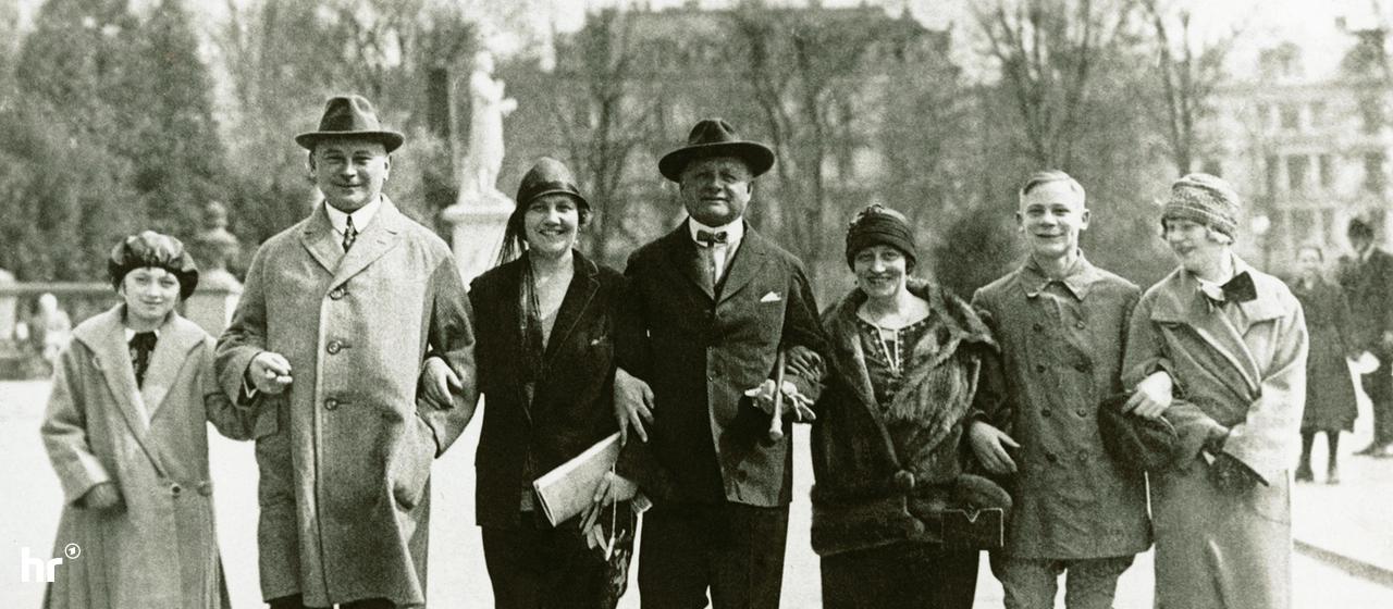 Sieben Menschen in Kleidung der 1920er Jahre Arm in Arm