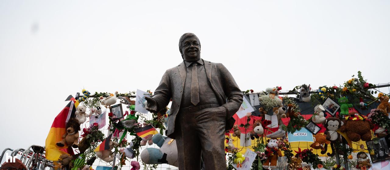 Eine Bronzestatue von Kassels ermordeten Regierungspräsident Walter Lübcke vor der Parteizentrale in Berlin. Im Hintergrund tausende Blumen und Kuscheltiere.