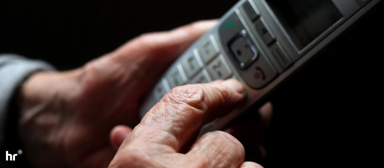 Hände einer älteren Frau halten einen Telefonhörer (Sujetbild)