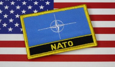 Ein NATO-Abzeichen liegt auf einer US-Flagge.