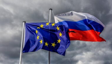 Europaflagge und Flagge der Russischen Föderation wehen vor grauem Himmel im Wind.