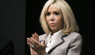 Macron im grauen Kostüm steht vor einem dunklen Hintergrund und klatscht in die Hände.