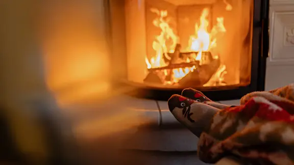 Eine Person sitzt mit warmen Socken vor einem Kaminofen. | photocase, Kay Fochtmann Eine Person sitzt mit warmen Socken vor einem Kaminofen.