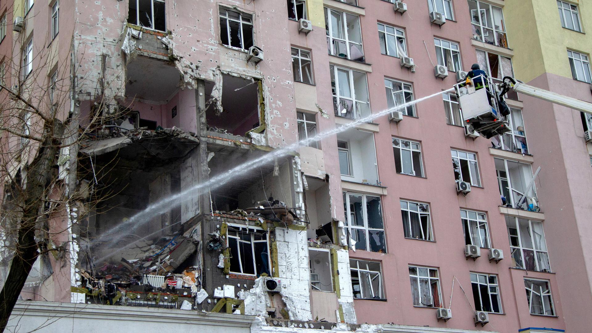 In der vergangenen Nacht gab es wieder massive russische Luftangriffe. Dabei wurden - wie hier in Kiew - viele Wohnhäuser stark beschädigt. In einem Haus klafft eine große Lücke, es brennt. Feuerwehrleute versuchen, zu löschen.
      