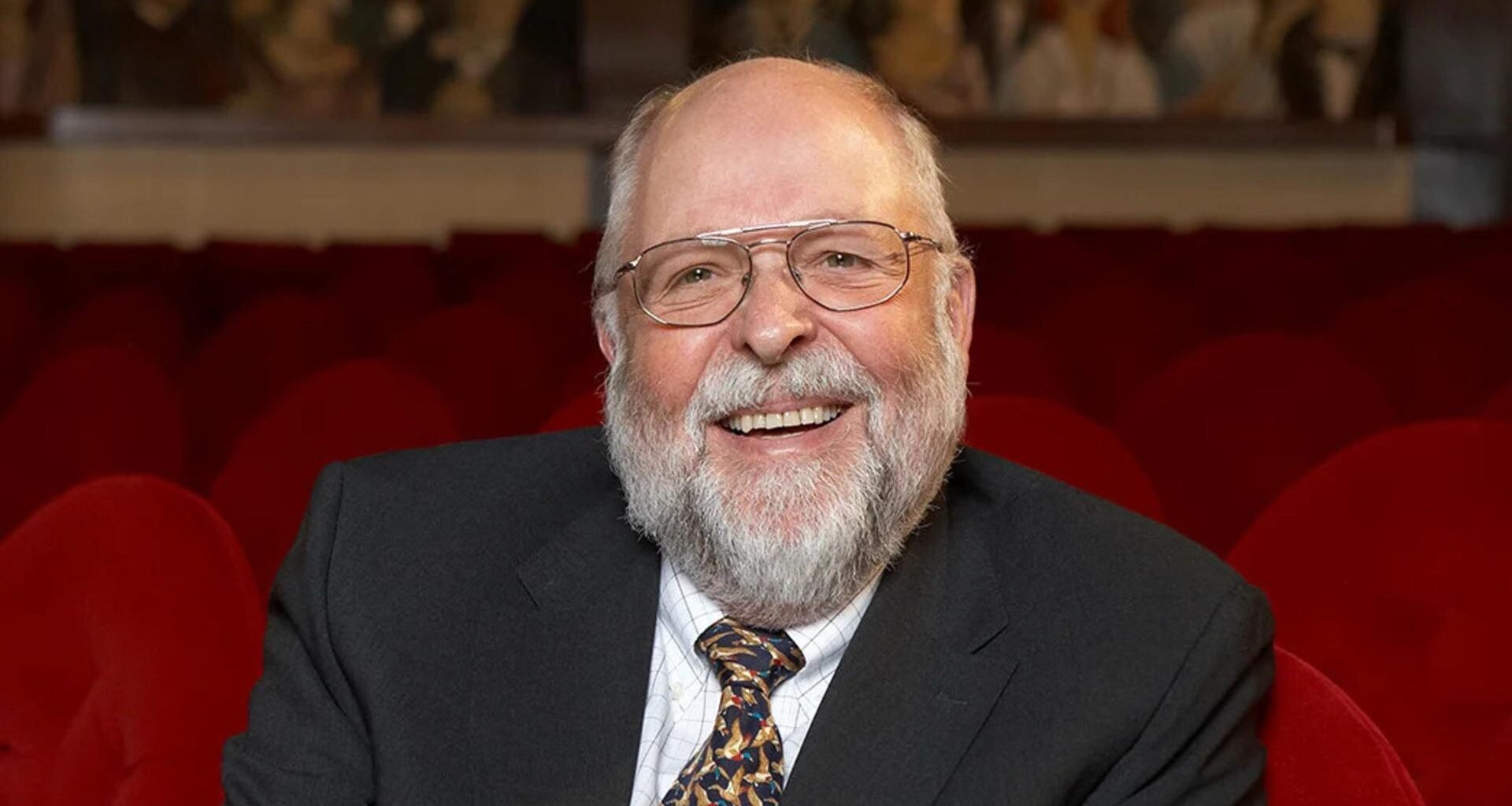 Klaus Tschira: Porträt als heiter lachender älterer Herr, mit Brille, Anzug, Krawatte und Vollbart