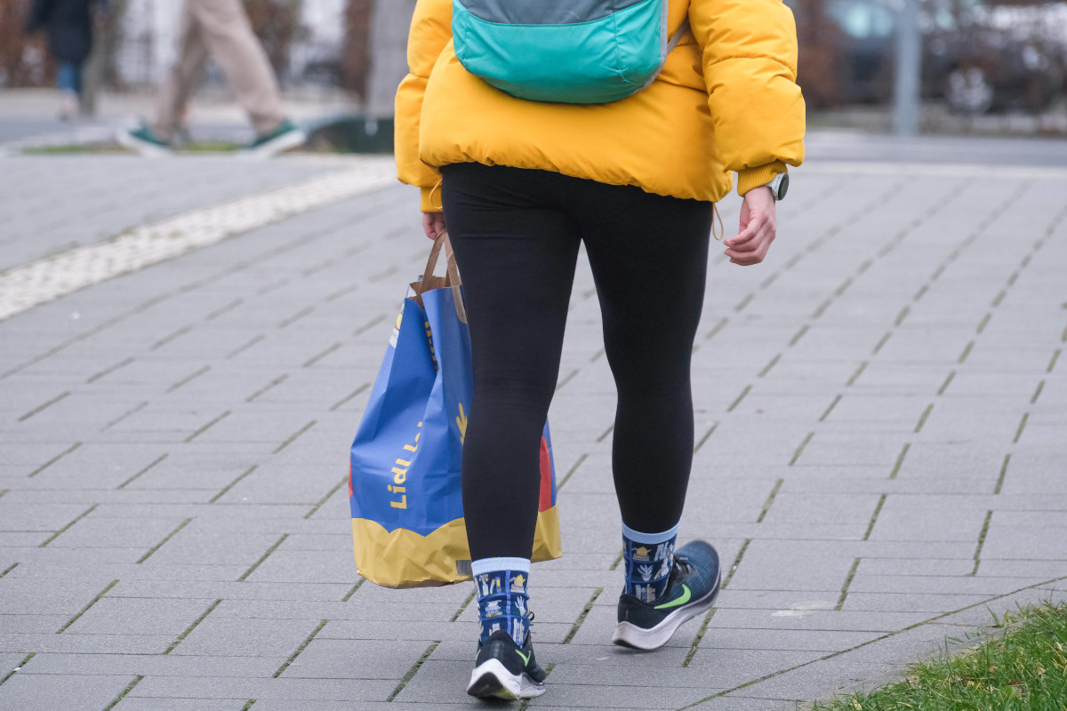 Eine Person mit einer Einkaufstüte in der Hand.