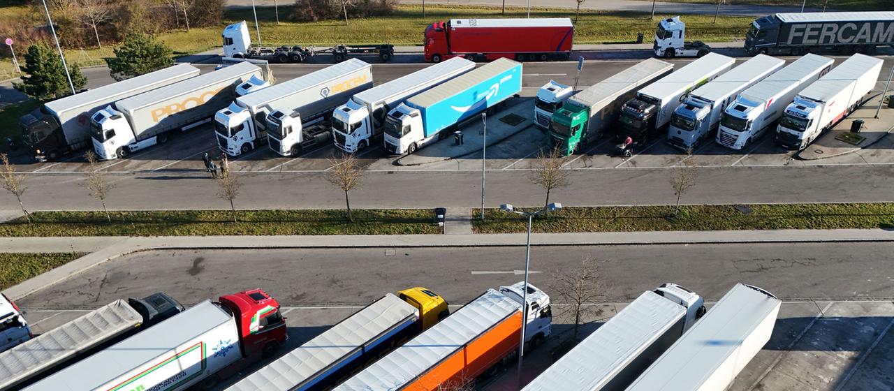 Lkw stehen auf dem Parkplatz einer Raststätte.