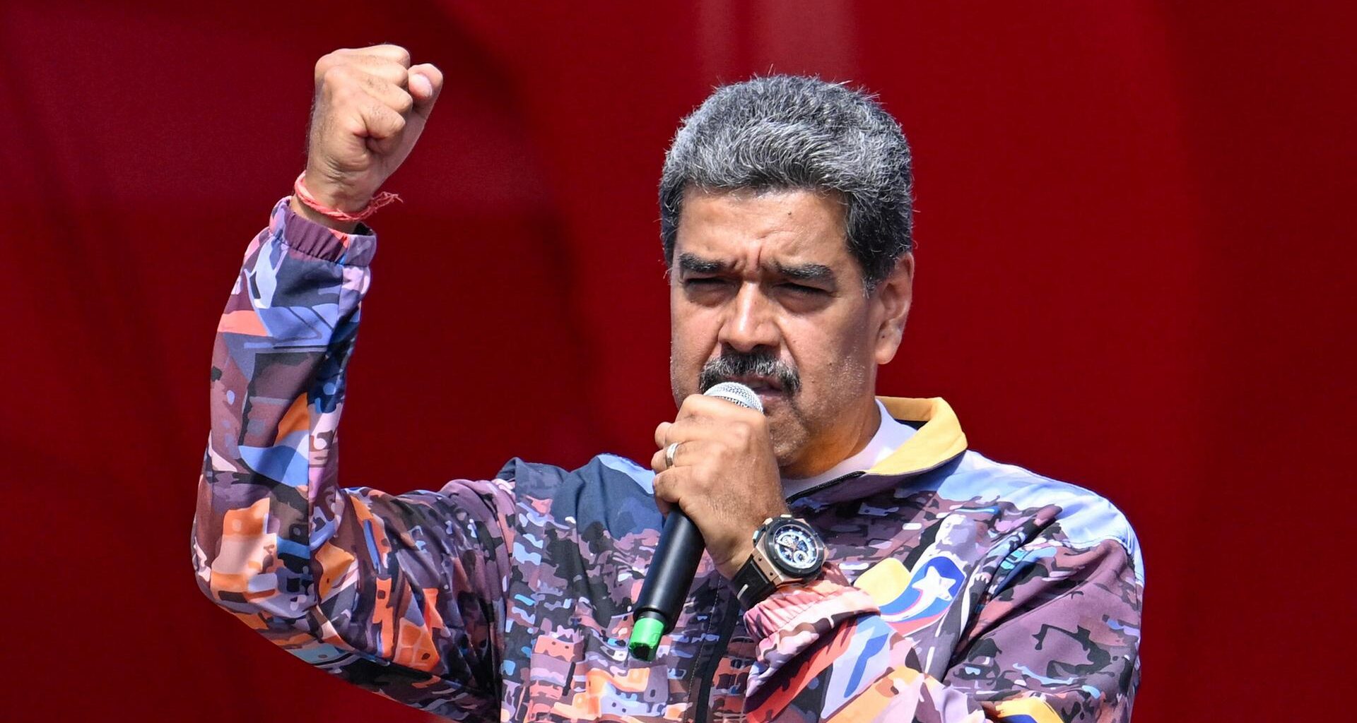 Maduro mit buntem Hemd und kämpferischer Geste bei einer Rede.