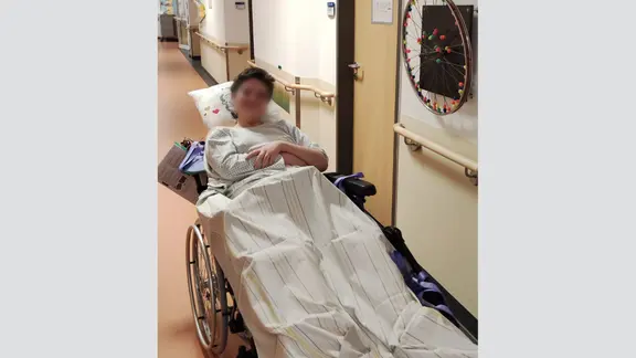 Das Bild zeigt einen Jungen, der in einem Bett im Krankenhaus liegt.